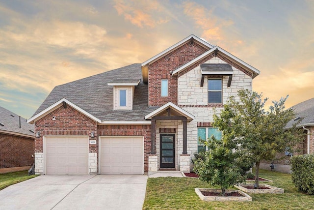 view of front of home with concrete driveway, a yard, a shingled roof, and stone siding