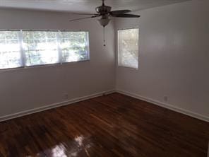 spare room featuring a wealth of natural light, dark hardwood / wood-style flooring, and ceiling fan