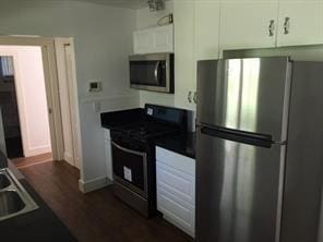 kitchen with white cabinets, stainless steel appliances, and dark hardwood / wood-style floors