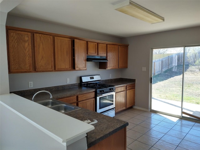 kitchen featuring light tile patterned floors, kitchen peninsula, stainless steel gas range oven, and sink