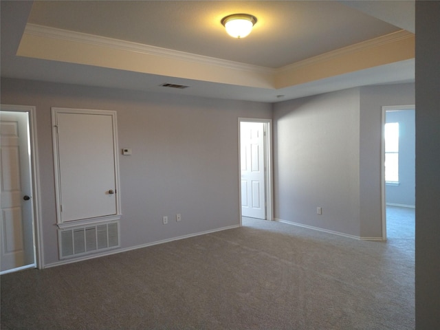 empty room featuring carpet floors, crown molding, and a raised ceiling