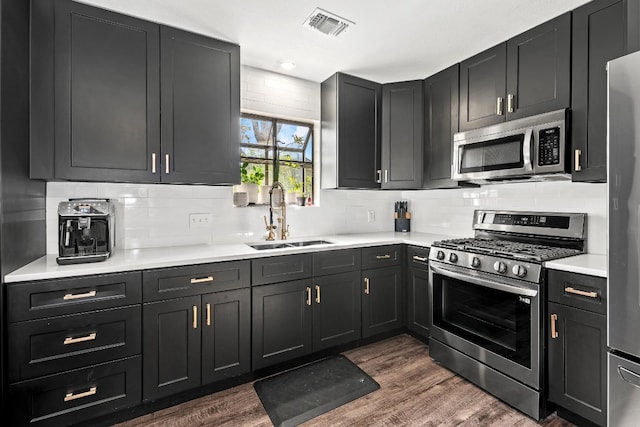 kitchen featuring appliances with stainless steel finishes, dark hardwood / wood-style flooring, tasteful backsplash, and sink