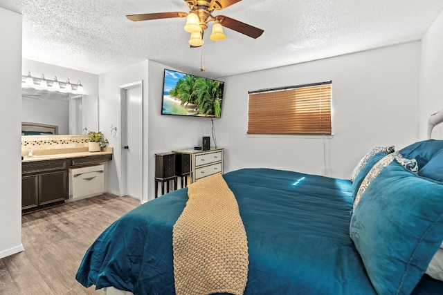 bedroom featuring connected bathroom, ceiling fan, light hardwood / wood-style flooring, and a textured ceiling