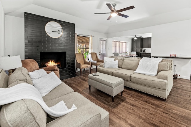 living room with a fireplace, lofted ceiling, and dark wood-type flooring