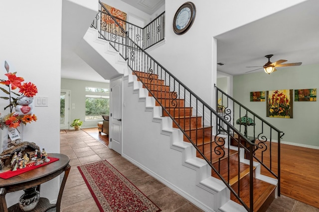 staircase featuring a towering ceiling, visible vents, baseboards, and a ceiling fan