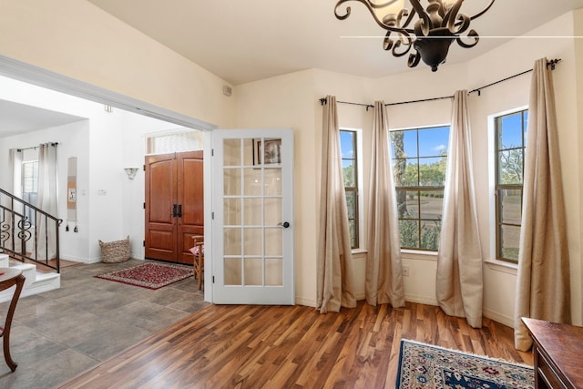 interior space with an inviting chandelier, baseboards, stairway, and wood finished floors