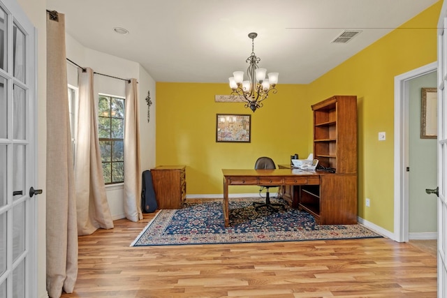 office space with a notable chandelier, wood finished floors, visible vents, and baseboards