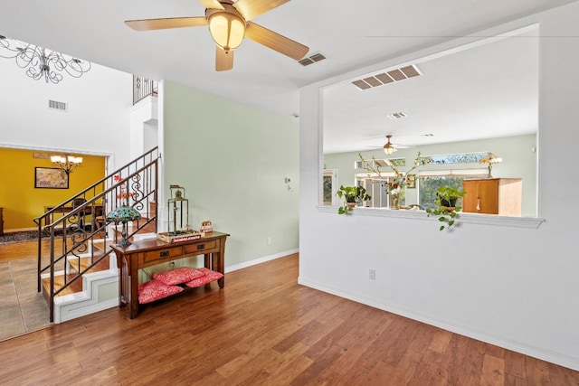 unfurnished room with stairway, wood finished floors, and visible vents