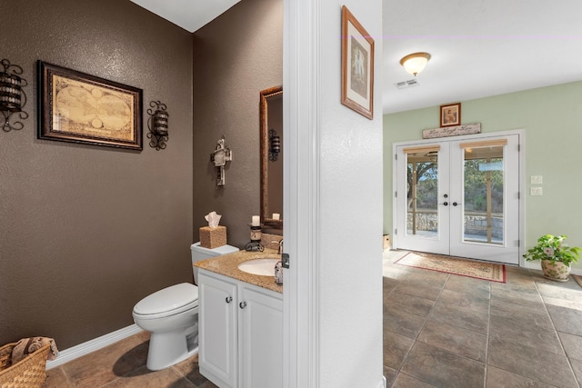 half bath featuring toilet, vanity, visible vents, baseboards, and french doors