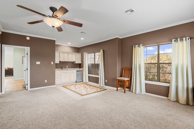 unfurnished living room with light colored carpet, visible vents, crown molding, and baseboards