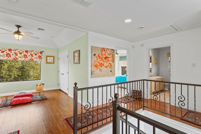 hallway with attic access, visible vents, wood finished floors, and an upstairs landing