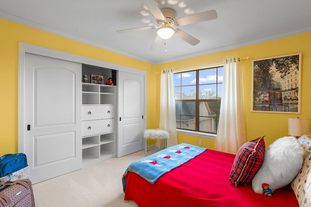 carpeted bedroom with ornamental molding, a closet, and a ceiling fan