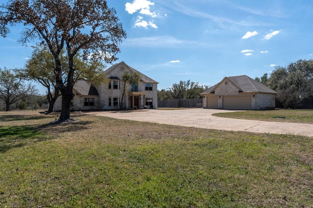 view of front facade featuring a garage, an outdoor structure, fence, driveway, and a front lawn