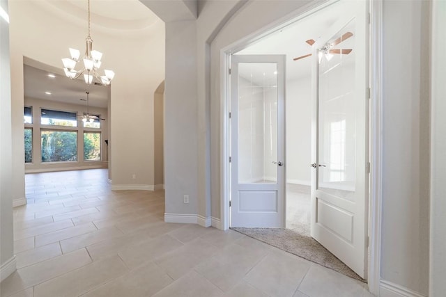 corridor with french doors, a chandelier, and light tile patterned floors