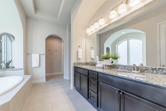 bathroom with vanity, tiled bath, tile patterned flooring, and a tray ceiling