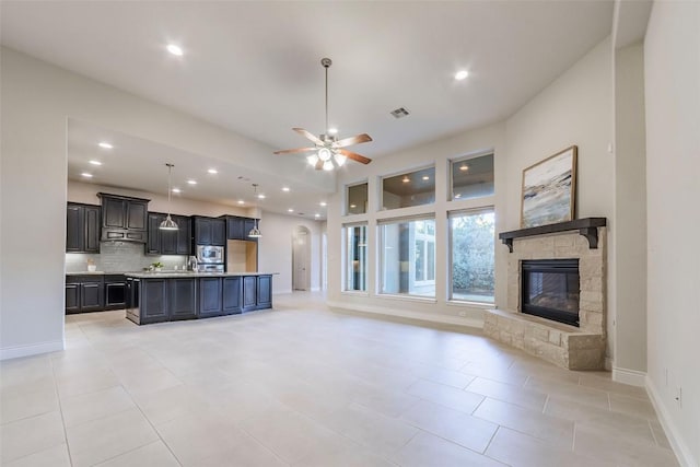 unfurnished living room with light tile patterned floors, a stone fireplace, and ceiling fan