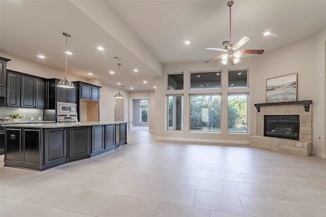 kitchen featuring a spacious island, hanging light fixtures, stainless steel appliances, a fireplace, and decorative backsplash