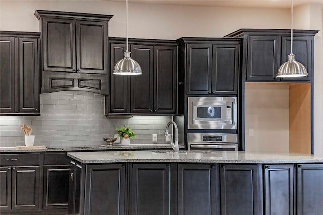 kitchen with tasteful backsplash, stainless steel appliances, decorative light fixtures, and sink