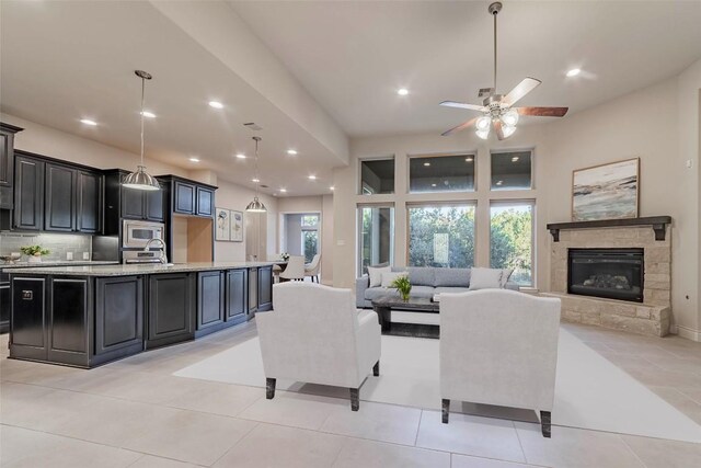 tiled living room featuring ceiling fan and a stone fireplace