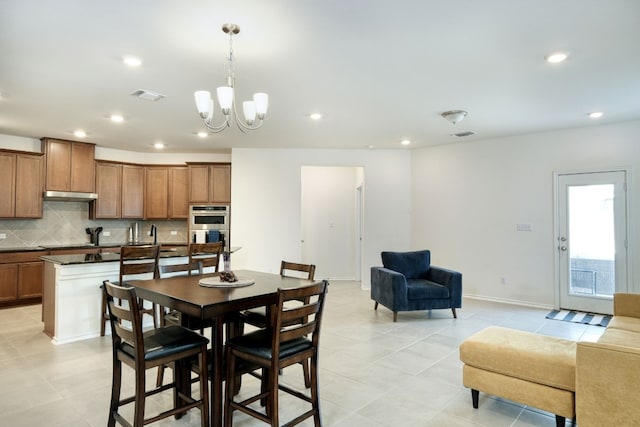 tiled dining space featuring sink and a chandelier