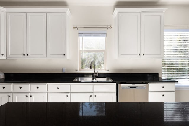 kitchen with stainless steel dishwasher, white cabinetry, sink, and a wealth of natural light