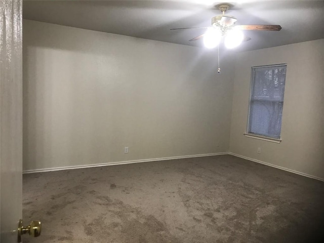 spare room with ceiling fan and dark carpet