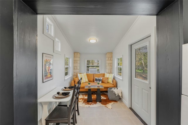 living area with crown molding, light tile patterned floors, and vaulted ceiling