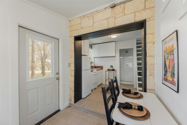 interior space with ornamental molding, white appliances, sink, light tile patterned floors, and white cabinetry