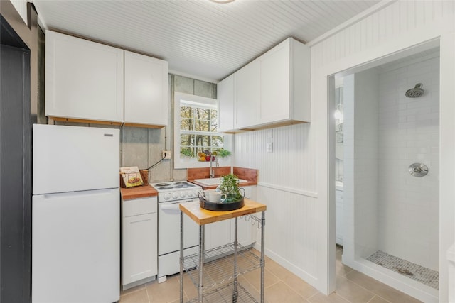 kitchen with white cabinetry, light tile patterned flooring, white appliances, and sink