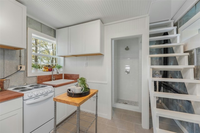 120 Laguna, Smithville, TX 78957 - kitchen featuring white electric range, wood counters, light tile patterned floors, and white cabinetry