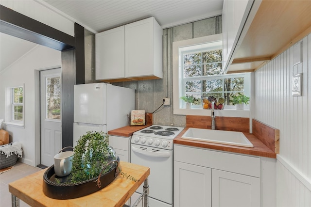 kitchen with white appliances, white cabinetry, vaulted ceiling, and sink