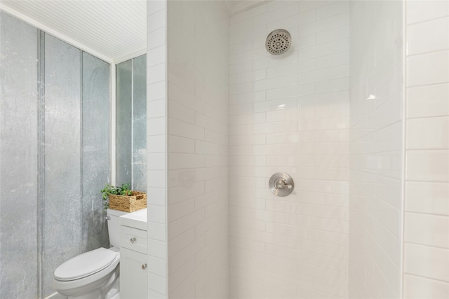 bathroom with toilet, vanity, and tiled shower