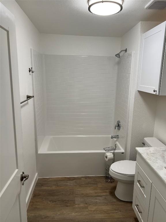 full bathroom with hardwood / wood-style floors, vanity, toilet, and tiled shower / bath