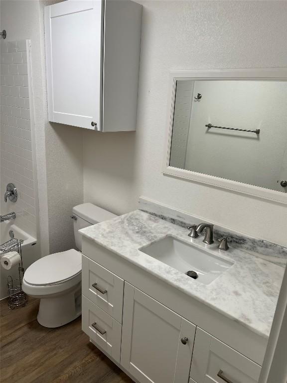 full bathroom featuring hardwood / wood-style floors, vanity, toilet, and bathing tub / shower combination