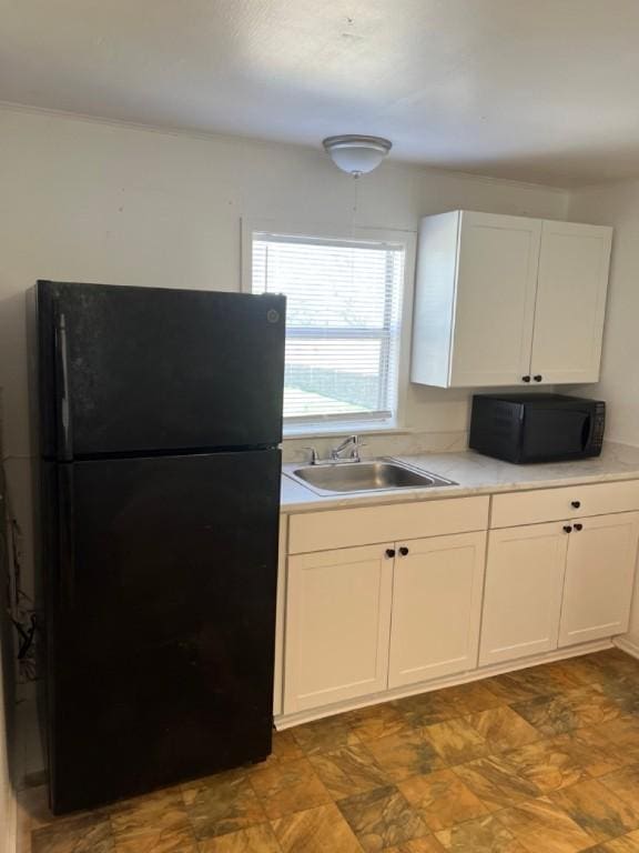 kitchen featuring white cabinetry, sink, and black appliances