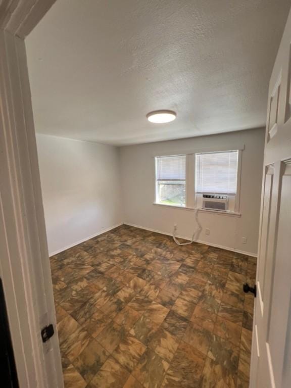 unfurnished room with cooling unit and a textured ceiling