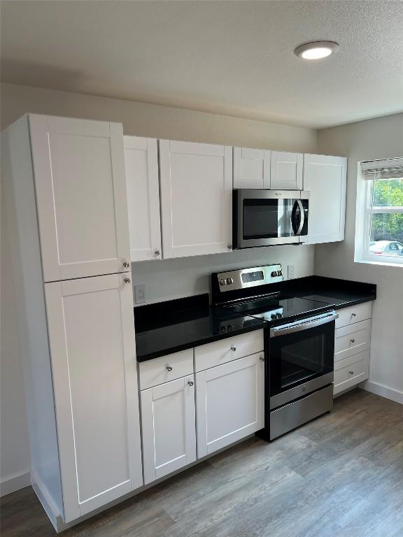 kitchen featuring white cabinets, light wood-type flooring, and appliances with stainless steel finishes