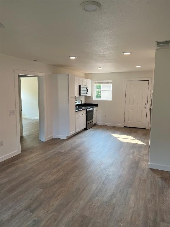 kitchen with dark hardwood / wood-style flooring, white cabinetry, and stainless steel appliances