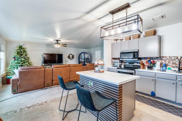 kitchen with appliances with stainless steel finishes, backsplash, a kitchen breakfast bar, a kitchen island, and hanging light fixtures