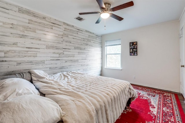 bedroom with ceiling fan and wooden walls