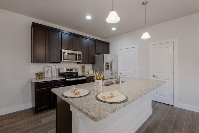 kitchen with dark brown cabinetry, a kitchen island with sink, hanging light fixtures, and stainless steel appliances