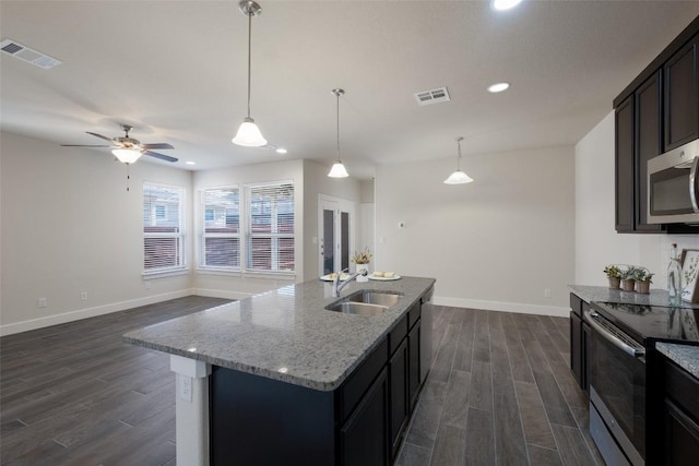 kitchen with a kitchen island with sink, sink, light stone countertops, dark hardwood / wood-style flooring, and stainless steel appliances