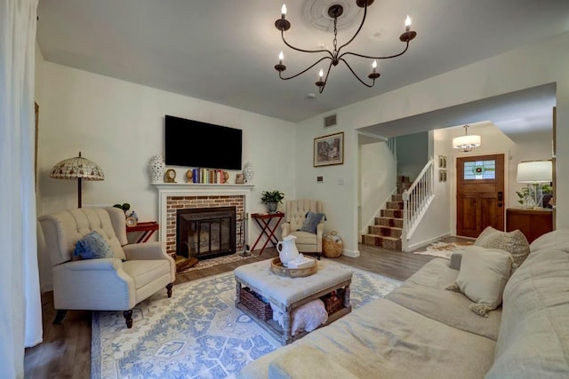 living room featuring a fireplace, wood-type flooring, and a notable chandelier