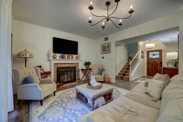 12323 Blue Water Dr, Austin, TX 78758 - living room with a chandelier, wood finished floors, stairway, and a brick fireplace