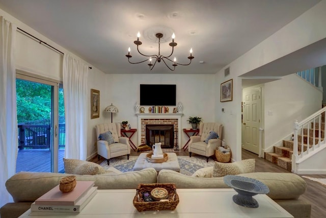 living room featuring a chandelier, hardwood / wood-style floors, and a brick fireplace