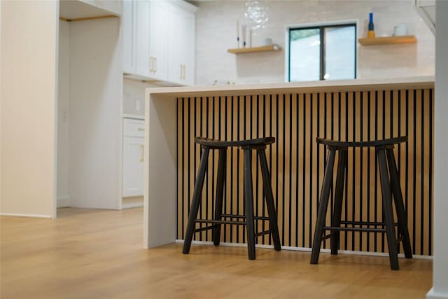 bar with white cabinets and light hardwood / wood-style flooring