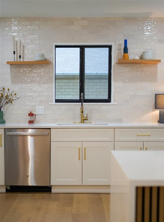 kitchen featuring sink, light wood-type flooring, dishwasher, decorative backsplash, and white cabinets