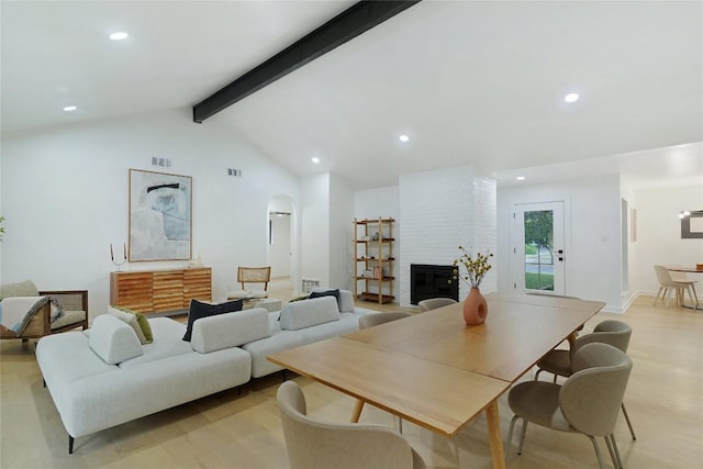 living room featuring light hardwood / wood-style flooring, vaulted ceiling with beams, and a fireplace