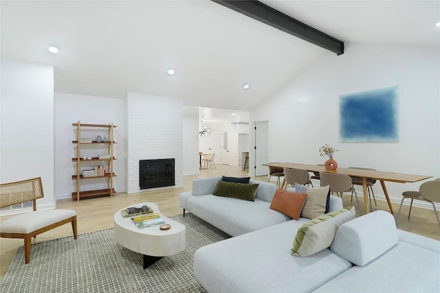 living room with beam ceiling, high vaulted ceiling, a large fireplace, and hardwood / wood-style flooring