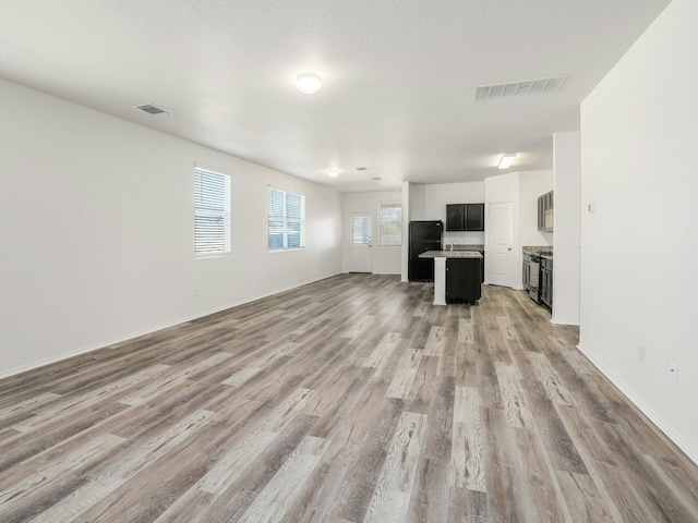 unfurnished living room featuring a textured ceiling and light wood-type flooring